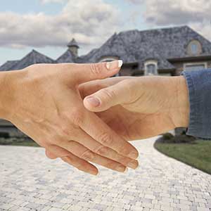 Two hands about to shake in front of a blurred out residential home in the background