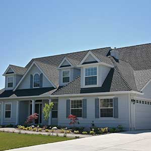Front view of a typical two-story, mid-class home with blue-ish siding and a gray shingle roof